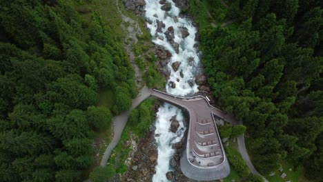 Vista-Aérea-De-Drones-Desde-Las-Cataratas-Gigantes-De-Agua-Grawa-Con-La-Plataforma-De-Observación-De-Madera-Con-Algunas-Personas,-Ubicadas-En-El-Valle-De-Stubai-En-Austria