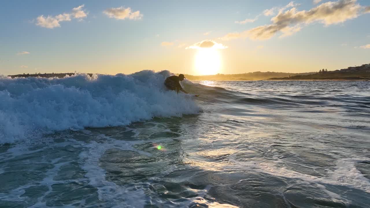 Aerial view of surfer riding wave, close up of waves breaking in slow motion with beautiful sunset. Water sports in South Pacific Ocean, natural sea landscape, surf, Sydney, Australia