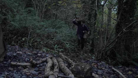 young man carries heavy logs from forest