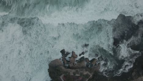 overhead drone shot of tidal waves moving toward on the rocky beach