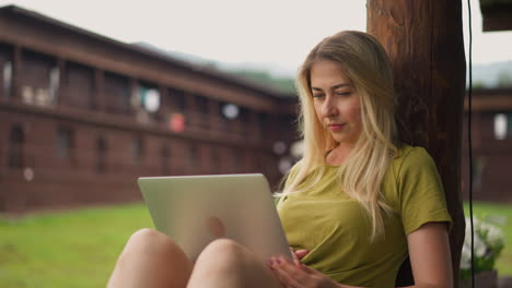 Attractive-lady-reads-news-in-social-media-laptop-on-terrace