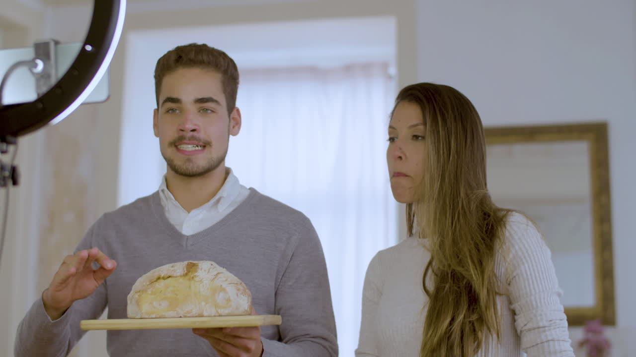 una pareja caucásica grabando un video para un vlog de cocina.