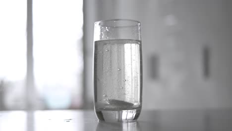 effervescent aspirin pill in a glass of wate. soluble tablet shot on super slow motion camera 1000 fps.