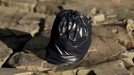 black-trash-bag-lay-on-a-rocky-beach