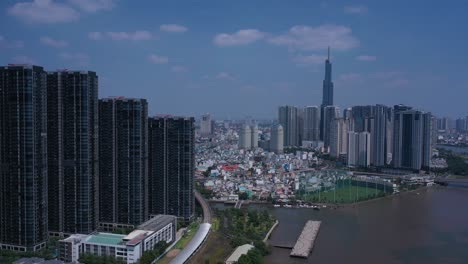 ho chi minh city, saigon river and binh thanh skyline on sunny, clear day featuring landmark building and golden river from drone tracking shot