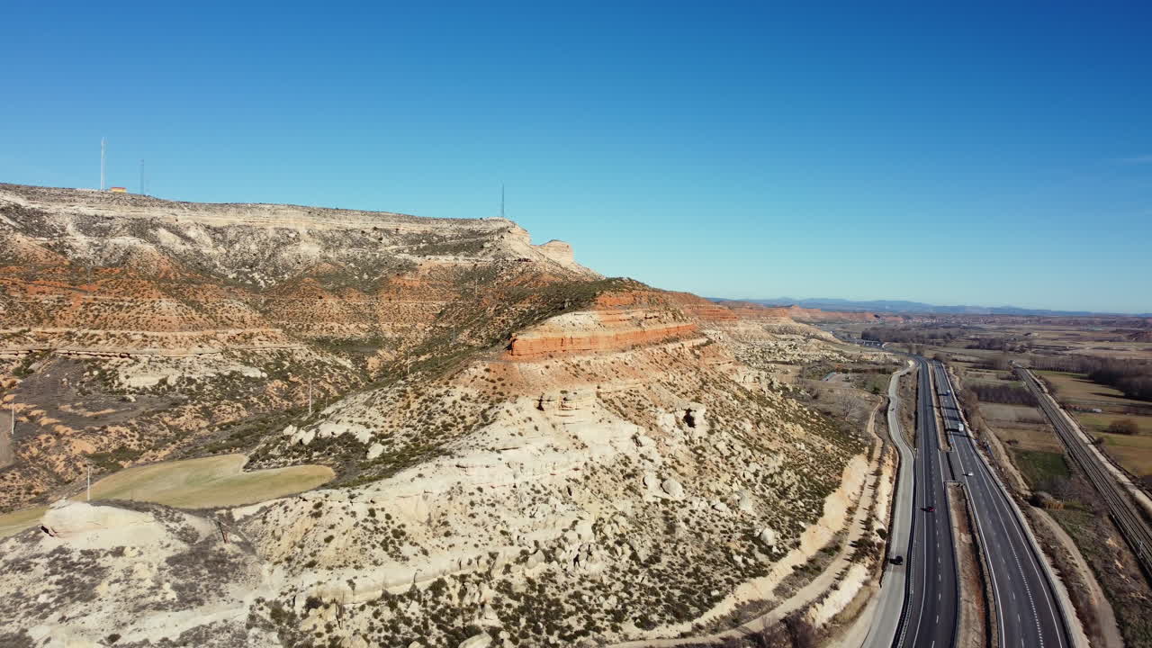 Aerial view of a highway winding through a desert landscape with mountains and canyons