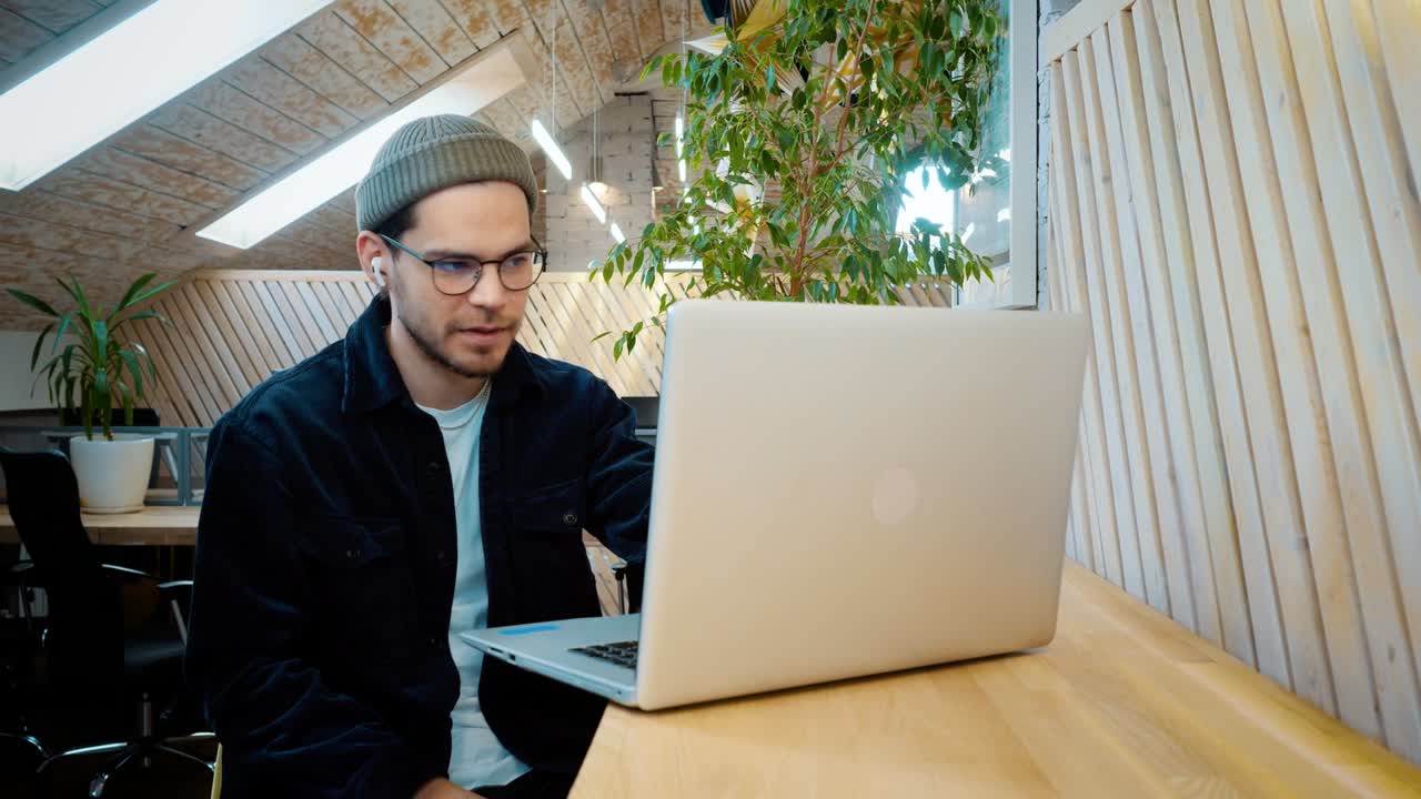 un joven se comunica a través de un enlace de video. riendo, bromeando. escucha al interlocutor