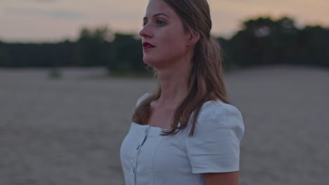 attractive woman walking through sand dunes with unique trees in the background