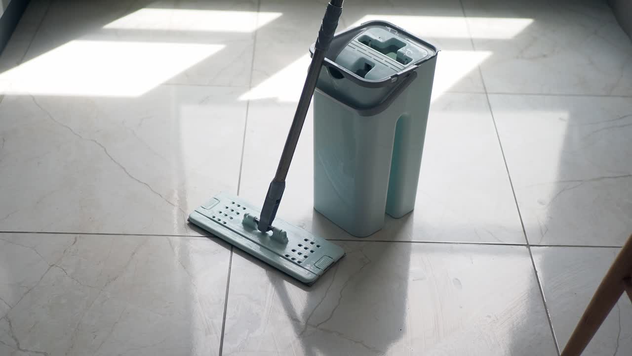 un trapeador azul y un cubo en un piso de azulejos