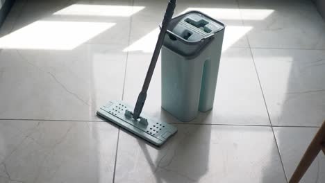 a blue mop and bucket on a tiled floor