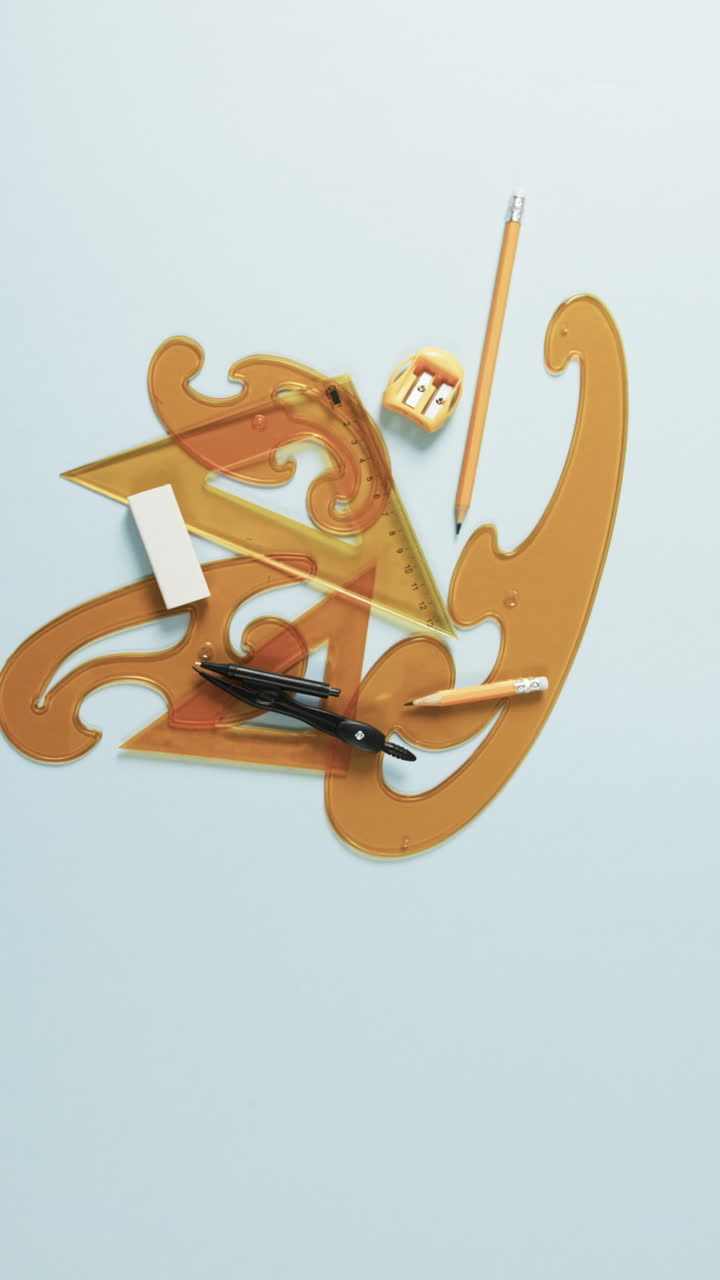 Vertical video of compass, pencil, sharpener, eraser and rulers on white background, slow motion