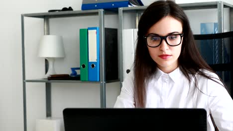 mujer de negocios quitándose las gafas negras y apoyando la cabeza con la mano en una oficina moderna
