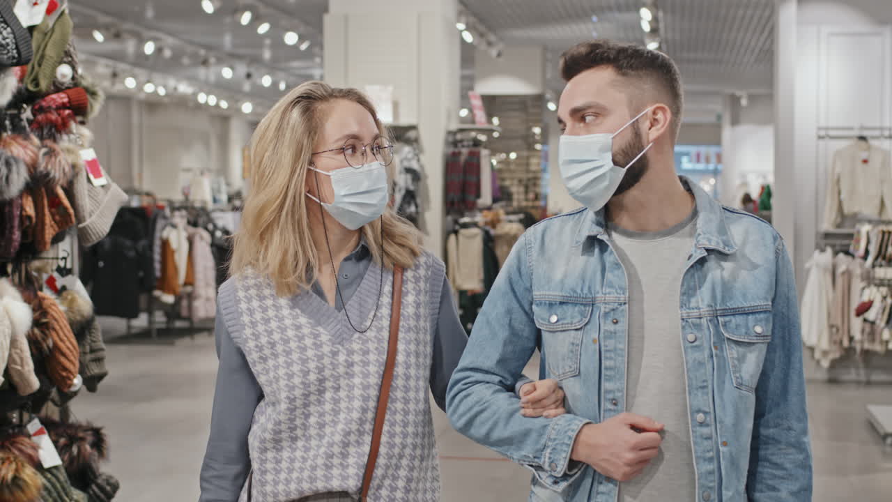 Stylish Couple In Face Masks Shopping At Clothing Store