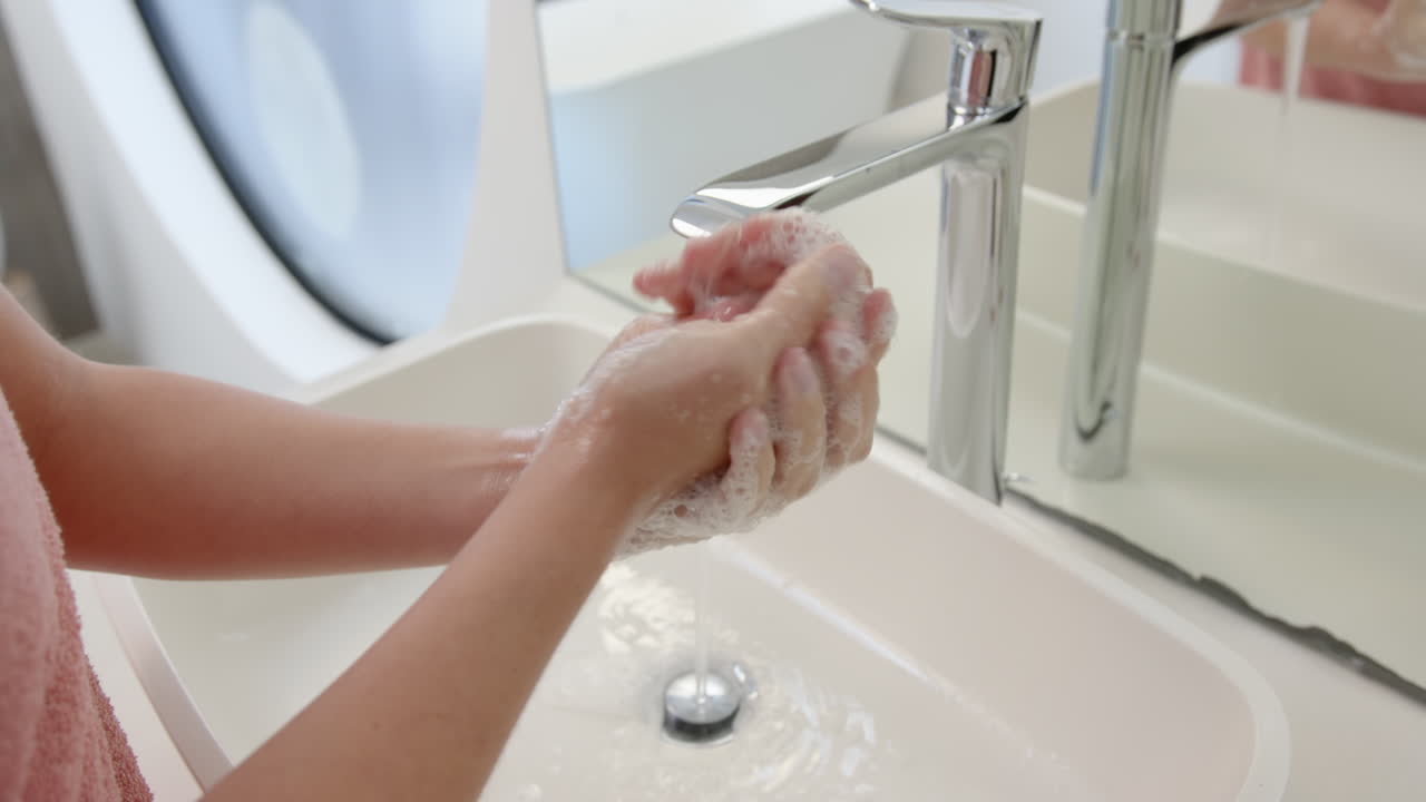 Washing hands with soap, person maintaining hygiene in modern bathroom