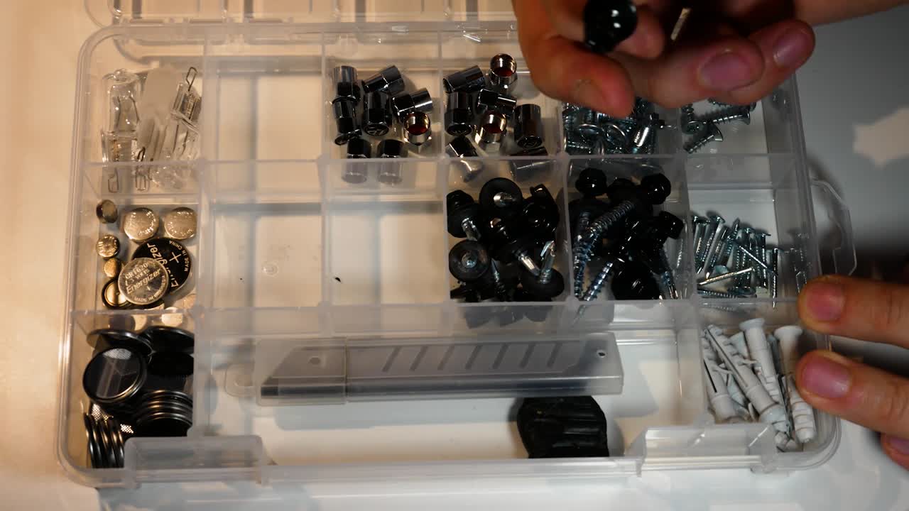 las manos del hombre están abriendo la caja de tornillos y no pueden encontrar el tornillo requerido, se enojan y cierran la caja