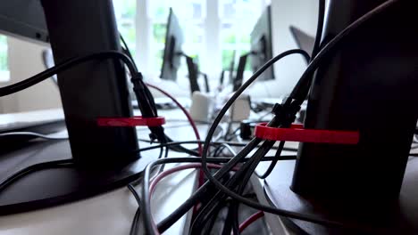 close-up of office desk setup with cables and wires organized behind monitors, highlighting workplace tech management