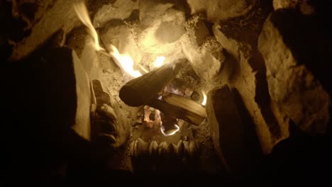 a top down view of wild foraged mussels slowly cook in front of an open log campfire in an old fireplace