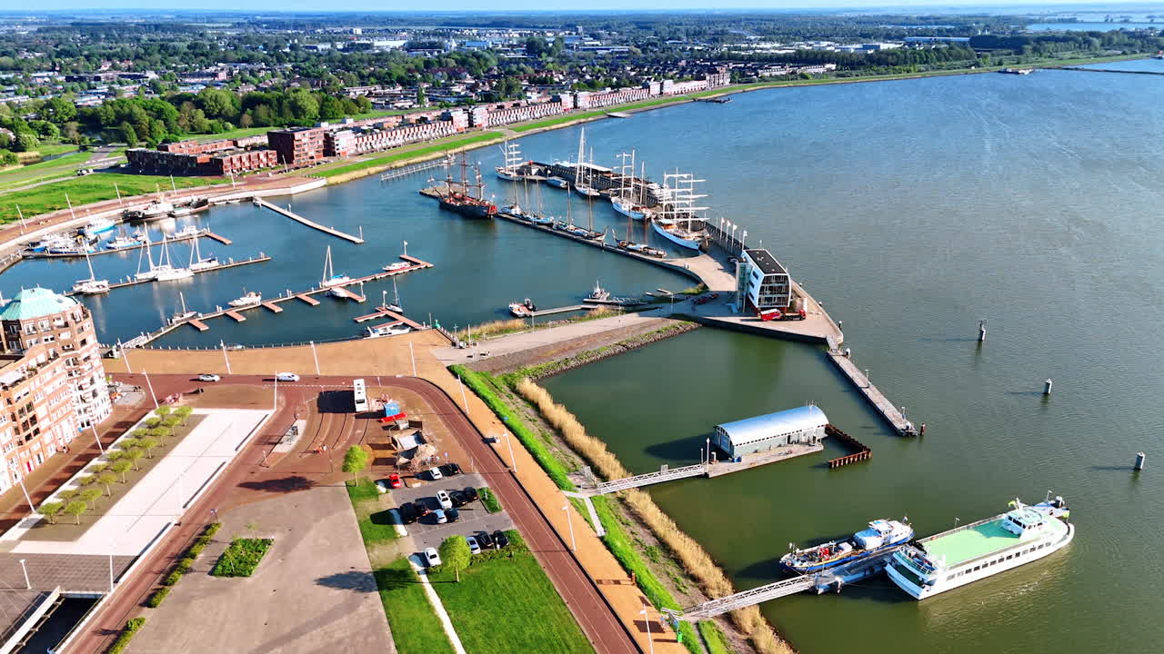 Port with berths at the waterfront of Lelystad, the Netherlands. Aerial perspective on lakefront of Lake Markermeer and cityscape with lush greenery.