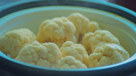 uncovering dish bowl with a steaming cauliflowers, close up