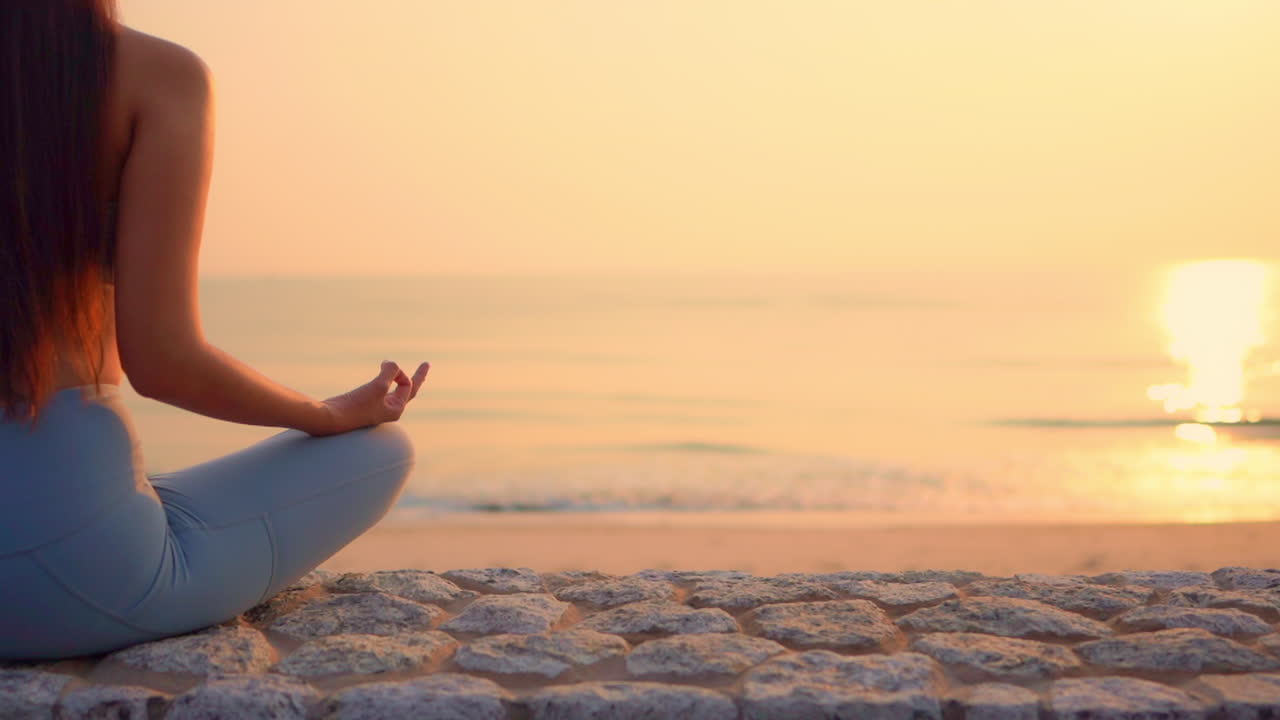 Alluring view of the sunset over a beach and beautiful young women meditating on the beach
