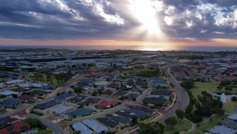 Luft-Hyper-Lapse-Des-Sich-ändernden-Lichts-Beim-Fliegen-über-Den-Vorort-Clarkson-In-Richtung-Mindari,-Während-Die-Wolken-Lichtstrahlen-über-Dem-Ozean-Erzeugen