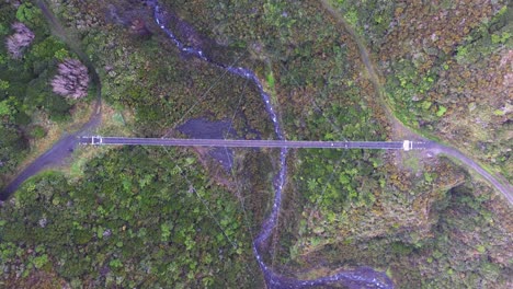 birdseye view above a large swing bridge as two cyclists rid across it