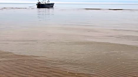 a boat is floating anchored in the calm ocean with a fishing gear on it