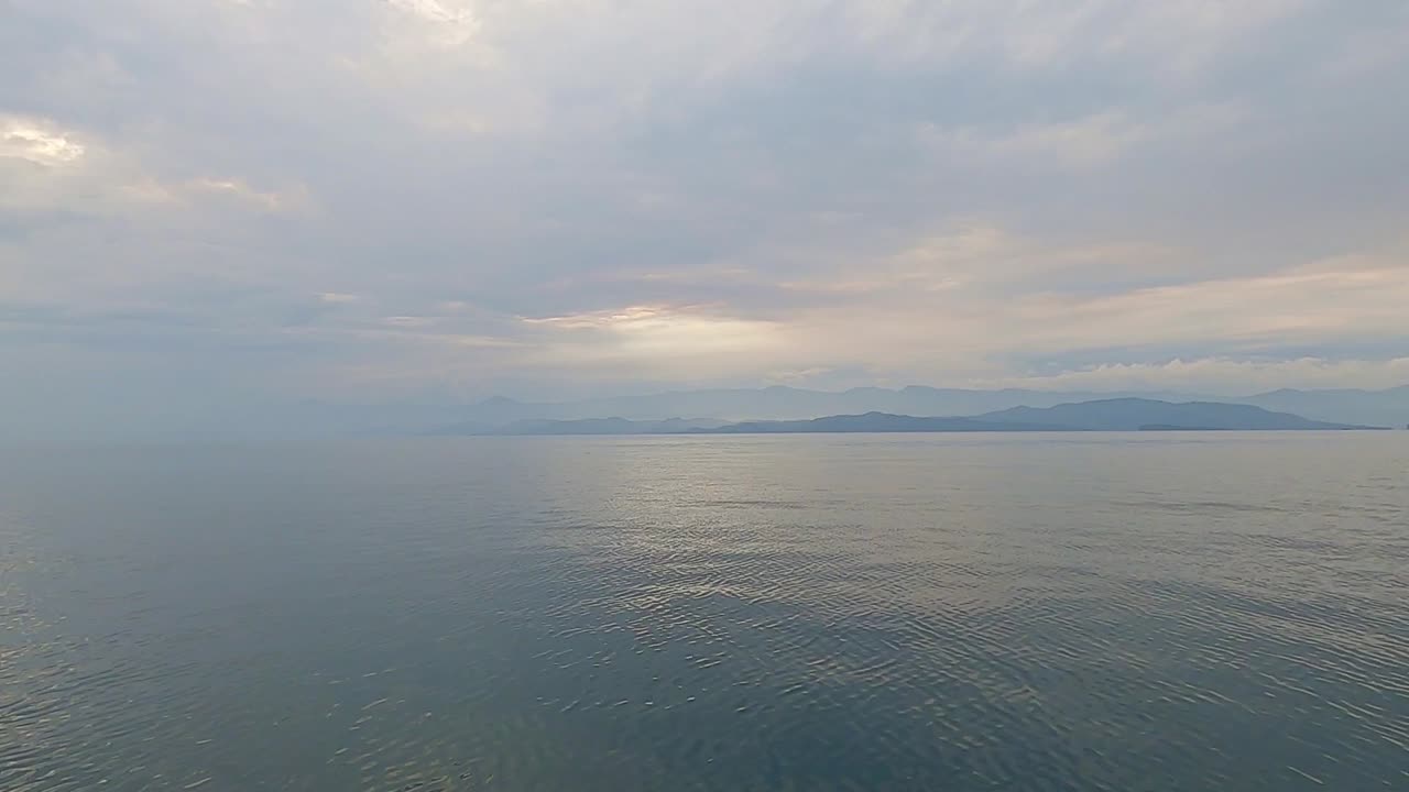 Wide angle POV of cruising above calm and peaceful sea in the evening