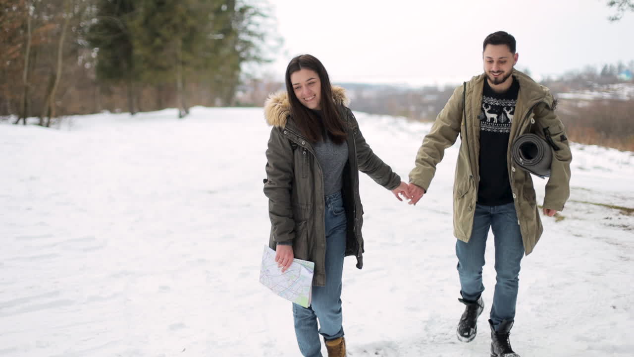 pareja caucásica caminando en un bosque nevado.