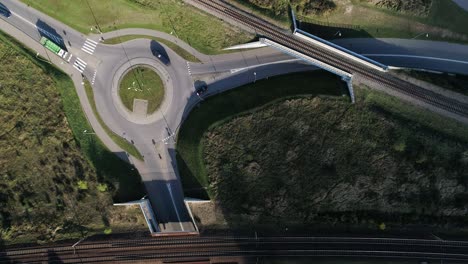 traffic circle on a paved road recorded from a drone on a sunny day along with the train tracks