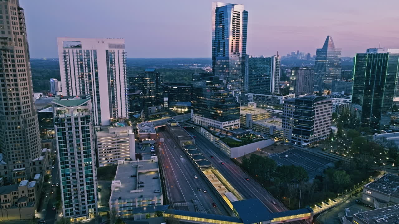 Drone establishing overview of large retail and commercial sector in Atlanta Buckhead under soft blue hour dusk sunlight glow, building lights shine on
