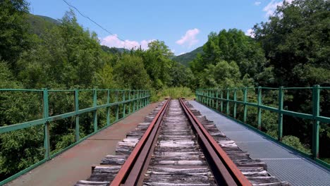 uma ferrovia velha e abandonada sobre uma ponte no campo - movimento para a frente ou ponto de vista do trem