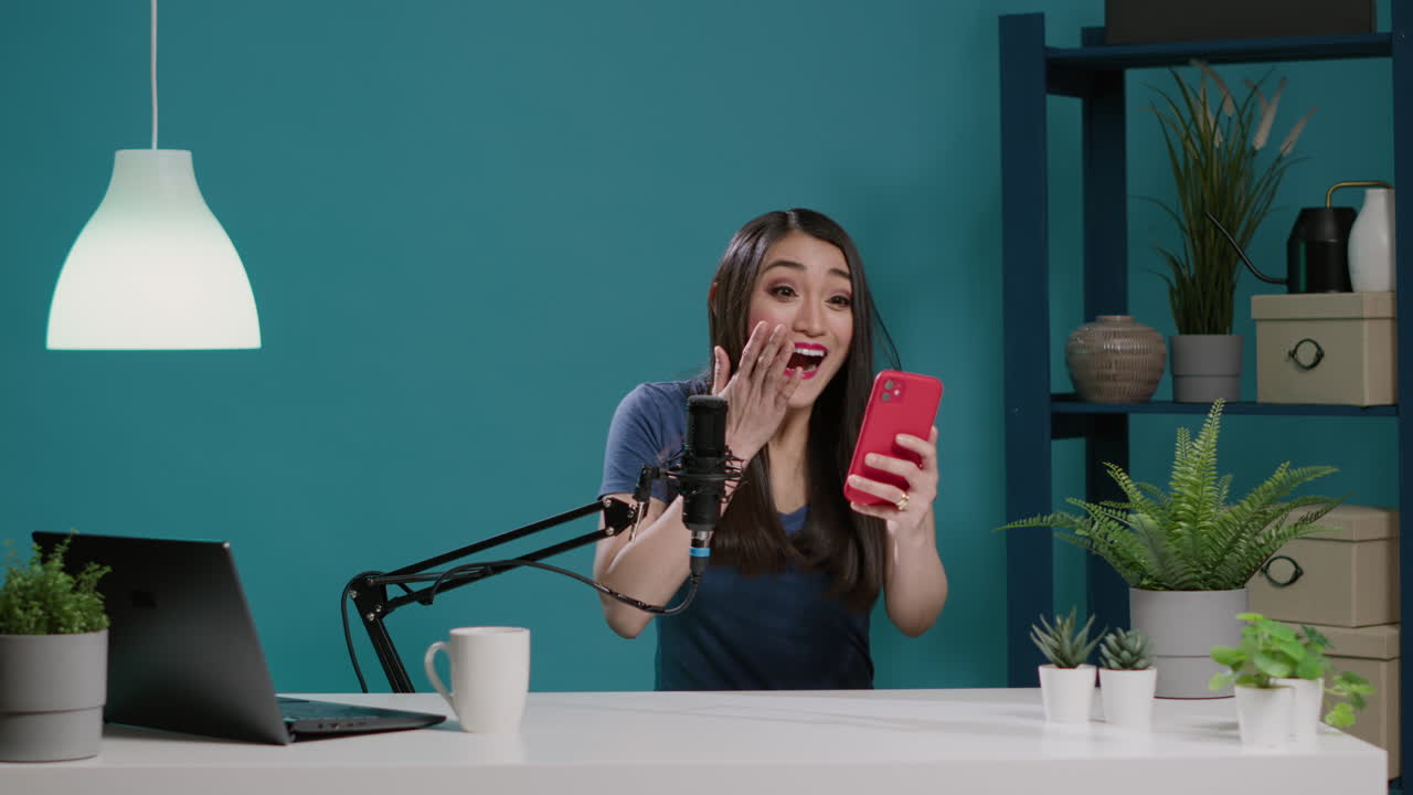 Asian vlogger reading comments with mobile phone on camera