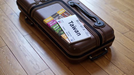 suitcase with taiwan guidebook on wooden floor