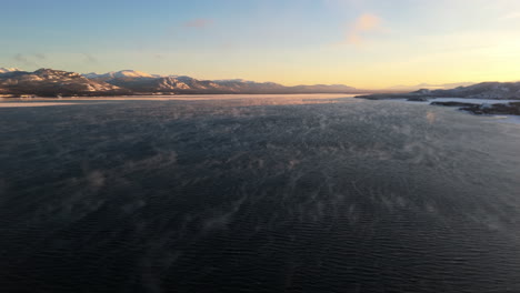 flying above lake laberge during sunset of winter in yukon, canada - drone shot