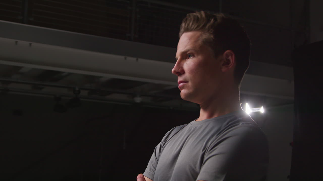 Serious Male Athlete Wearing Fitness Clothing Training And Preparing Psychologically For Sports Event In Gym With Low Key Lighting