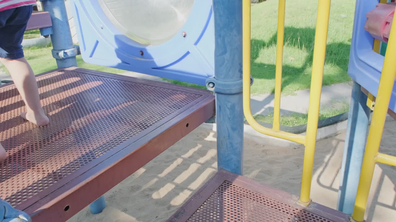 Active little sisters are running in the outdoor playground in the park. Happy child girls smiling and laughing on children playground. The concept of play is learning in childhood.