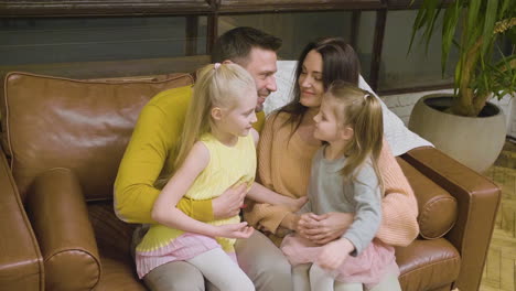 familia feliz sentada en el sofá de casa y abrazándose unos a otros