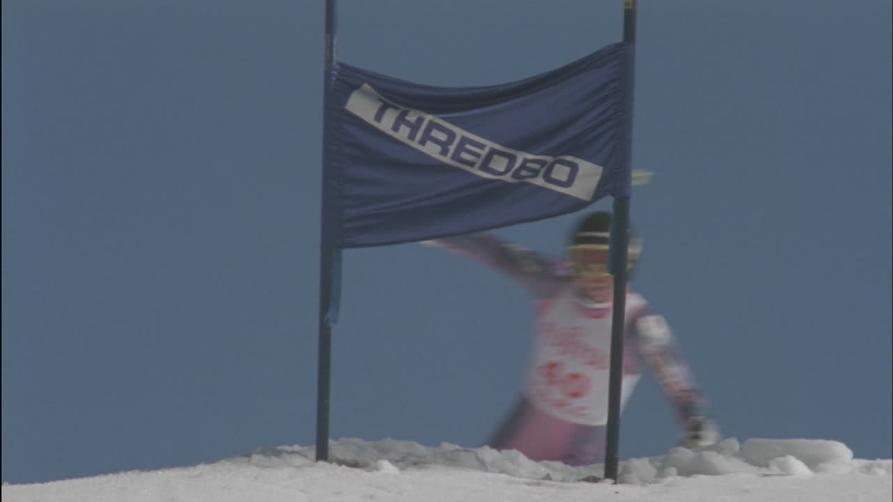 경쟁적인 스키 선수가 언덕 아래로 스키를 타고 눈송이가 날아갑니다.