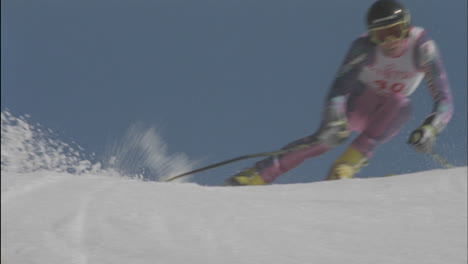 a competitive skier skis down a hill and snowflakes fly