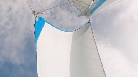 low angle shot of genoa jib sail and mast against cloudy sky, wind blowing, day