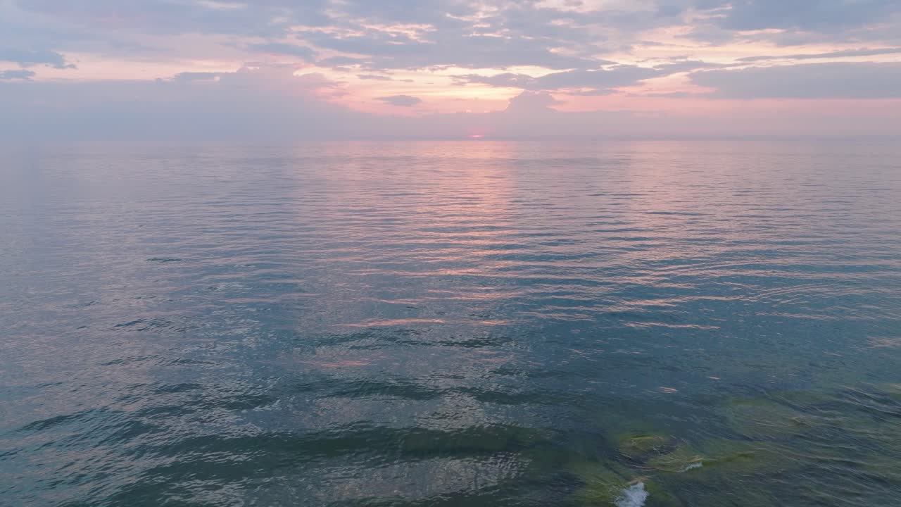 평온한 발트해 위의 활기찬 높은 대조적인 일몰의 아름다운 공중 전망, 지평선에 구름, 카로스타 전쟁 항구 콘크리트 해안 요새 폐허 리파자, 넓은 드론  ⁇  앞으로 낮게 이동
