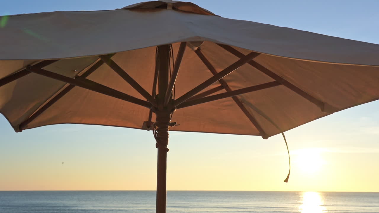 Pan across canvas beach, shade umbrella to setting sun