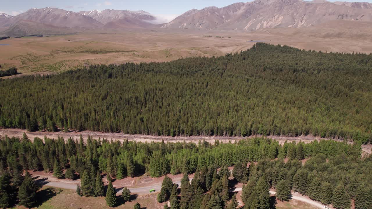 полет назад, чтобы показать озеро текапо с горами и соснами на заднем плане