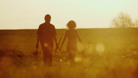 steadicam shot: farmers - a man and a woman walking across the field at sunset