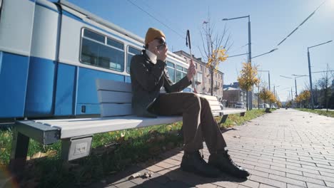 visually impaired man talking on the phone, sitting on the bench in the city.