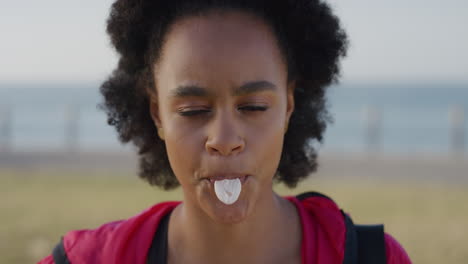 Portait-Animada-Joven-Afroamericana-Soplando-Burbujas-De-Chicle-Disfrutando-De-Diversión-Lúdica-Riendo-Feliz-Chica-Negra-De-Vacaciones-Junto-Al-Mar-Fondo-De-Playa