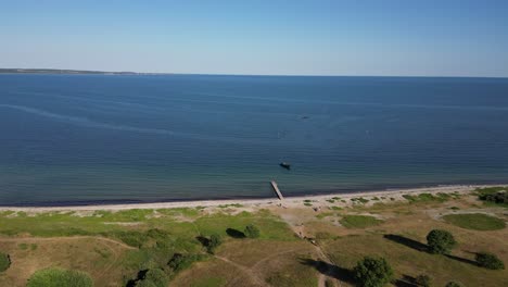 Drone-recording-over-the-water-at-Mol's-mountains,-motorboat-is-about-to-dock-at-the-small-jetty