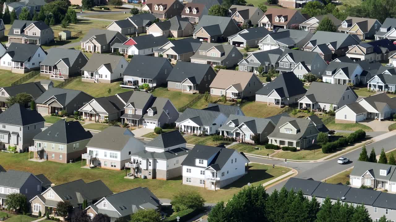 Moderne case unifamiliari in una zona residenziale americana in una giornata di sole. Stagione estiva con giardini ben curati. Facciata bianca e architettura con tetto grigio. Zoom aereo con scatto ampio