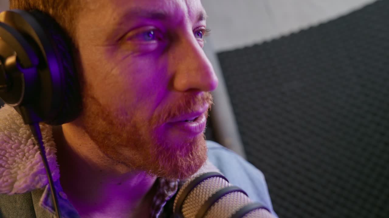 hombre en estudio de sonido grabando programa de podcast en vivo o sesión de radio con micrófono y auriculares profesionales. la cámara se mueve cerca con ángulo amplio. anfitrión genial hablando con los invitados con entusiasmo